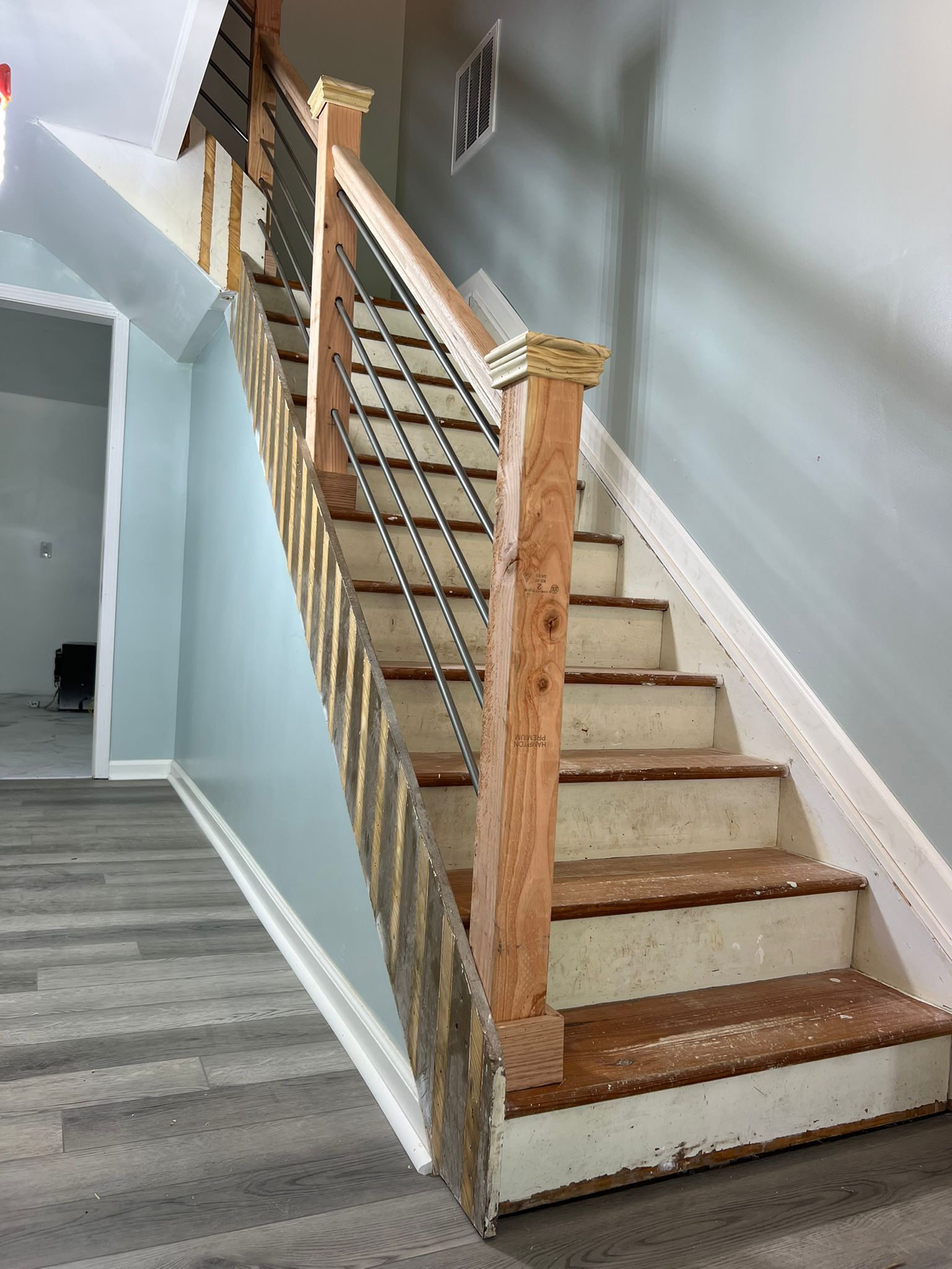Staircase with tan carpeted steps, wooden handrails, and blue-gray walls in a home interior