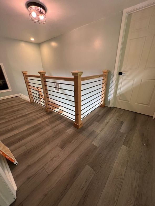 Stair landing with wood railings, gray floors, white walls, and a closed door