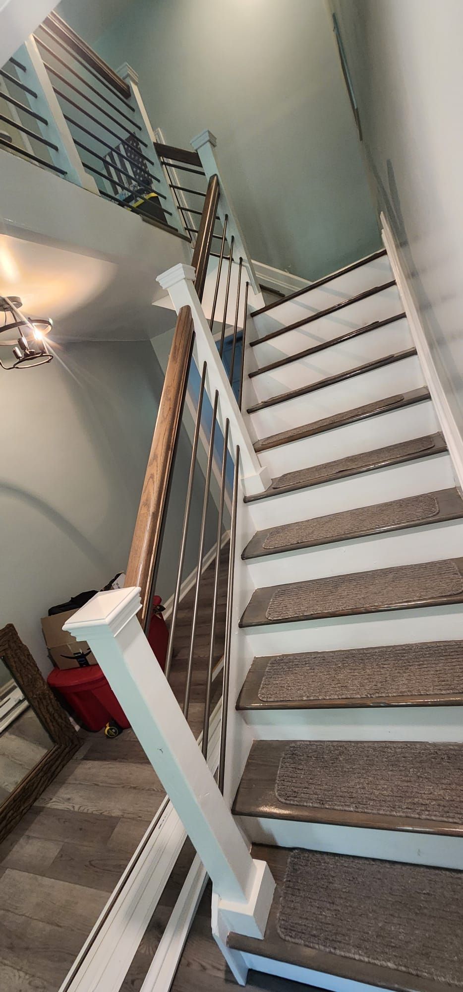 Staircase with white railings and carpeted steps in a home interior, viewed from the bottom looking up.
