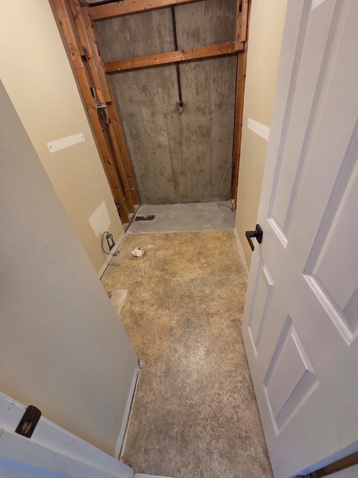 Narrow hallway with open doorways leading to a small unfinished closet or utility space with exposed wood.