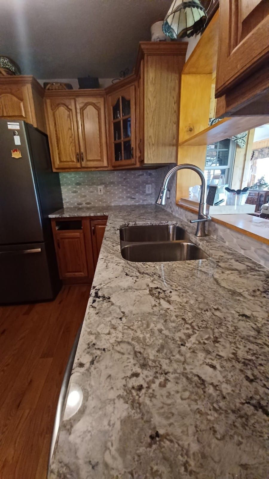 Kitchen with granite countertops, wood cabinets, and a double sink by a bright window.