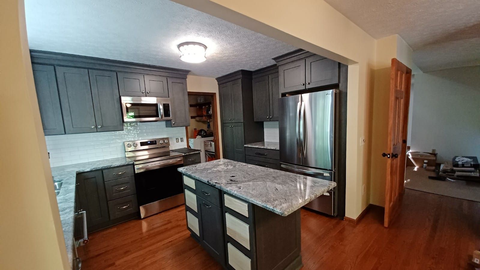 Modern kitchen with dark cabinets, granite island, stainless steel appliances, and hardwood floors