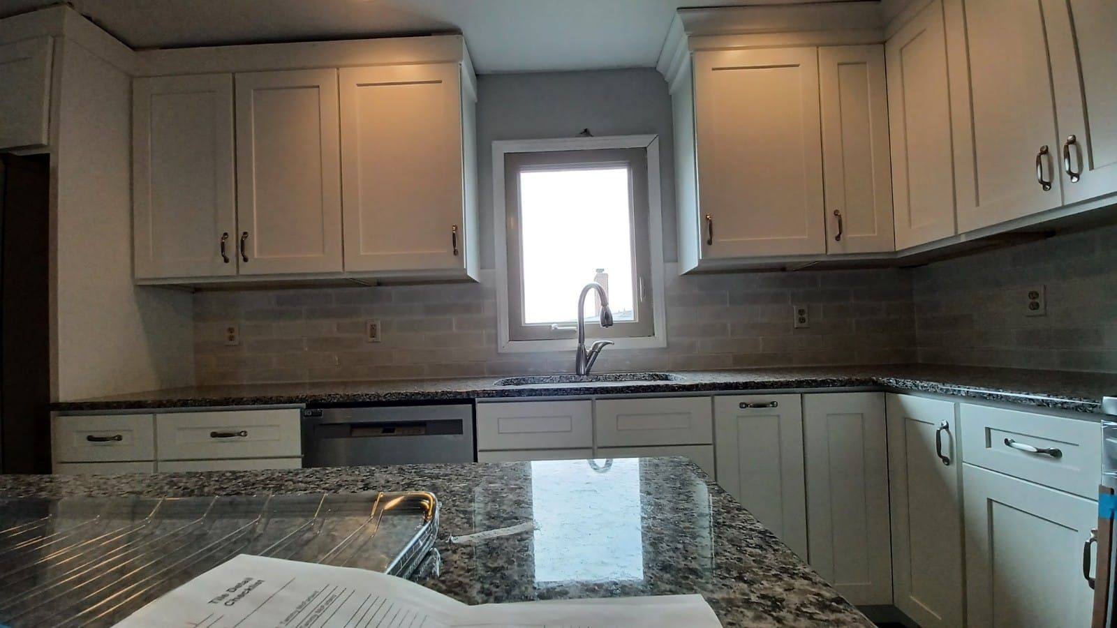 Modern kitchen with white cabinets, granite countertops, stainless appliances, and a window over the sink
