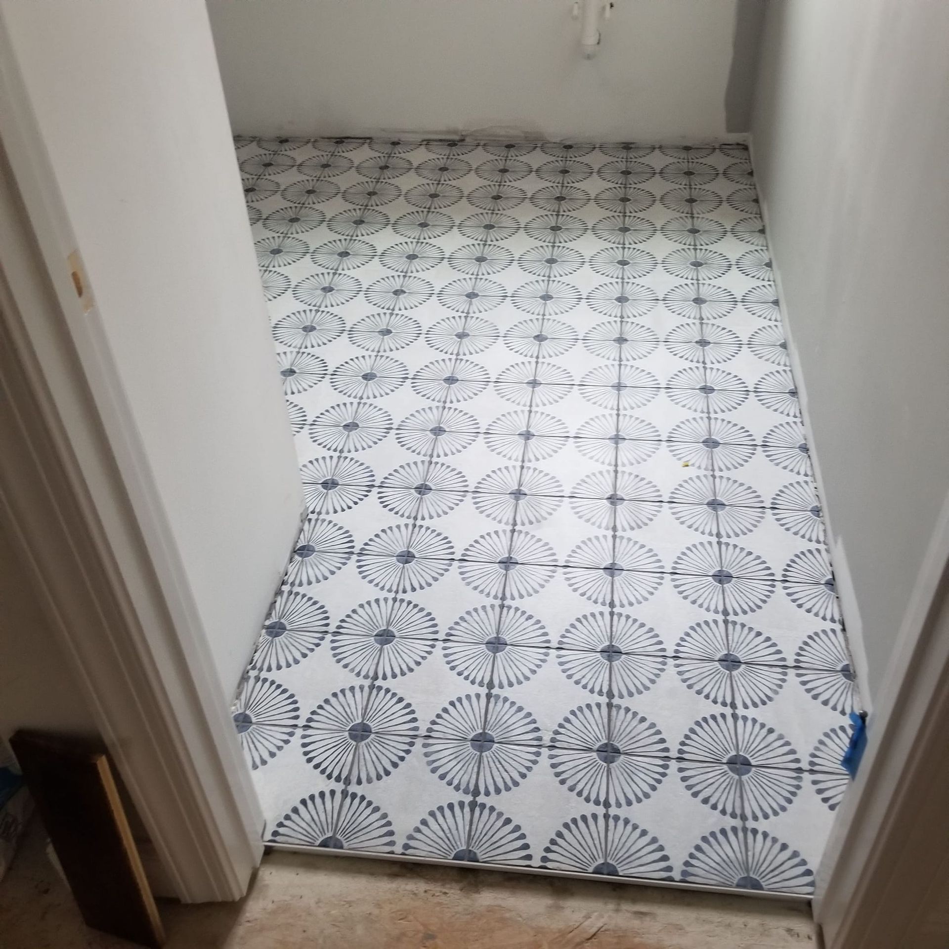 Small tiled room with white-and-black patterned floor and plain white walls, viewed from the doorway