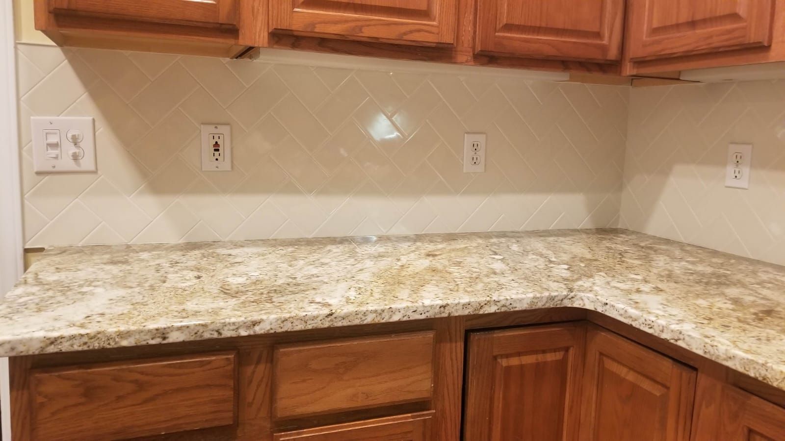 Corner kitchen countertop with speckled granite and wooden cabinets underneath
