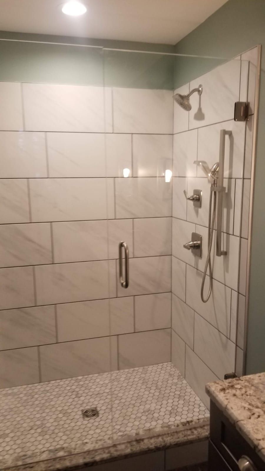 Tiled walk-in shower with glass door, built-in bench, and chrome shower fixtures
