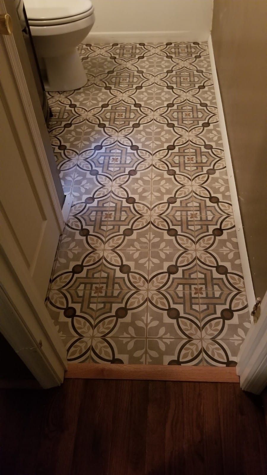 Narrow bathroom doorway with patterned vinyl floor and a toilet visible at the left.