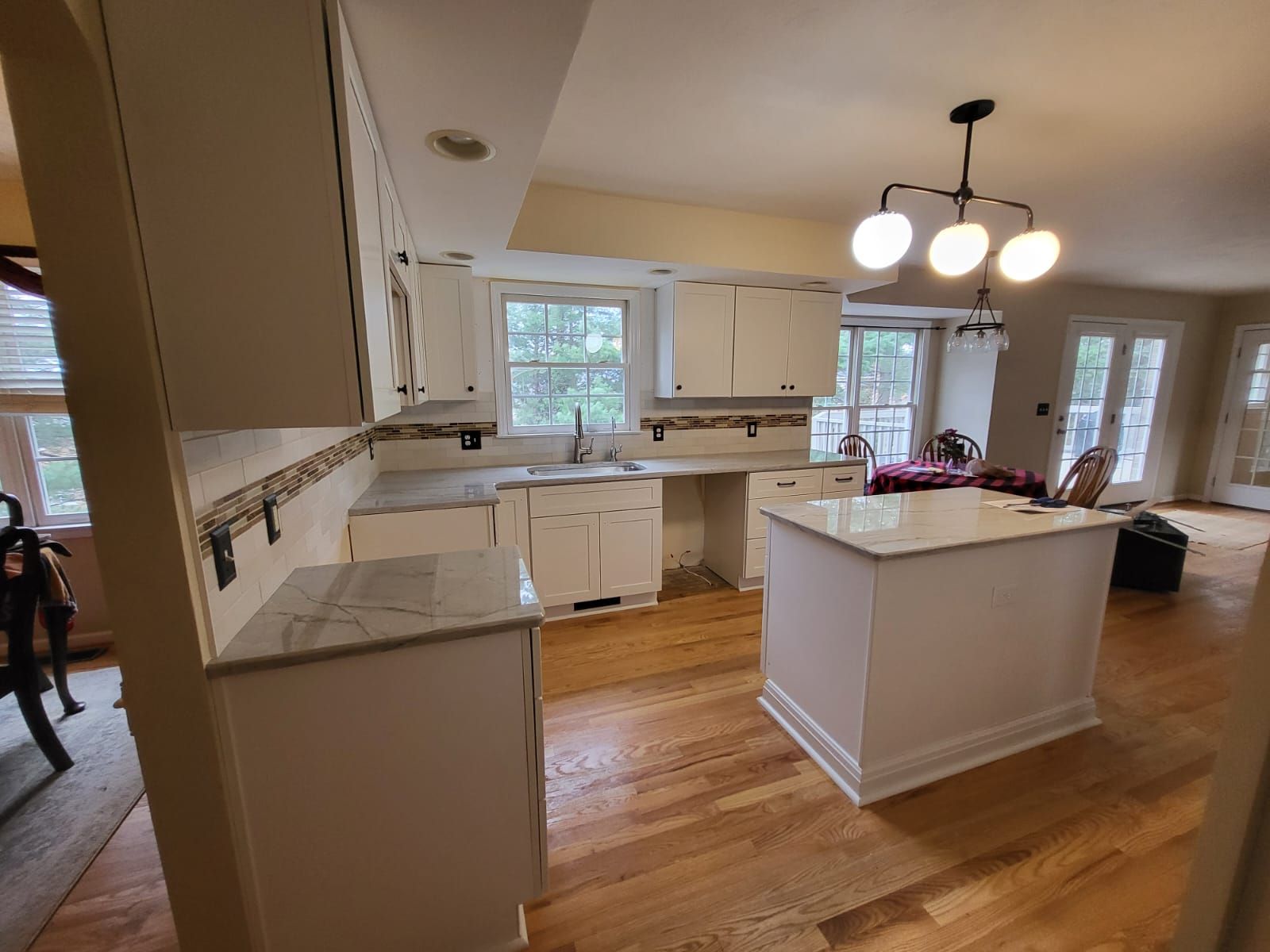 Bright kitchen with white cabinets, center island, hardwood floors, and pendant lights