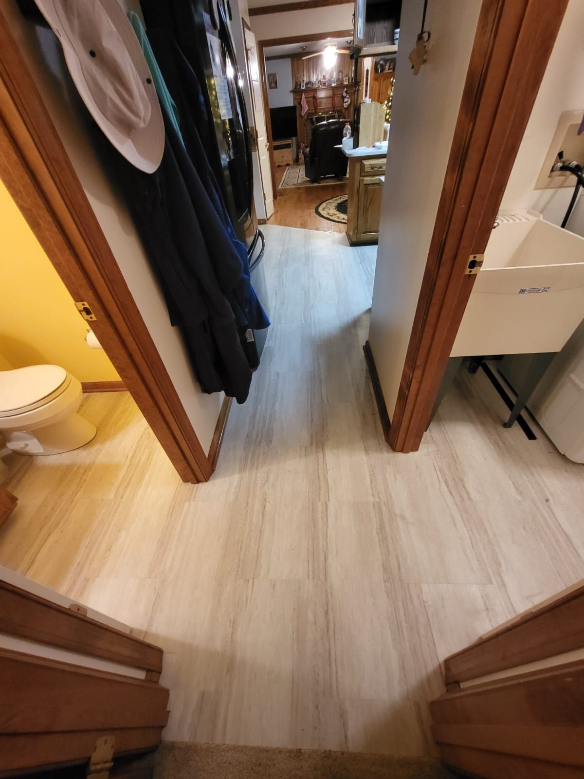 Hallway view into a walk-in closet with hanging clothes and light wood flooring