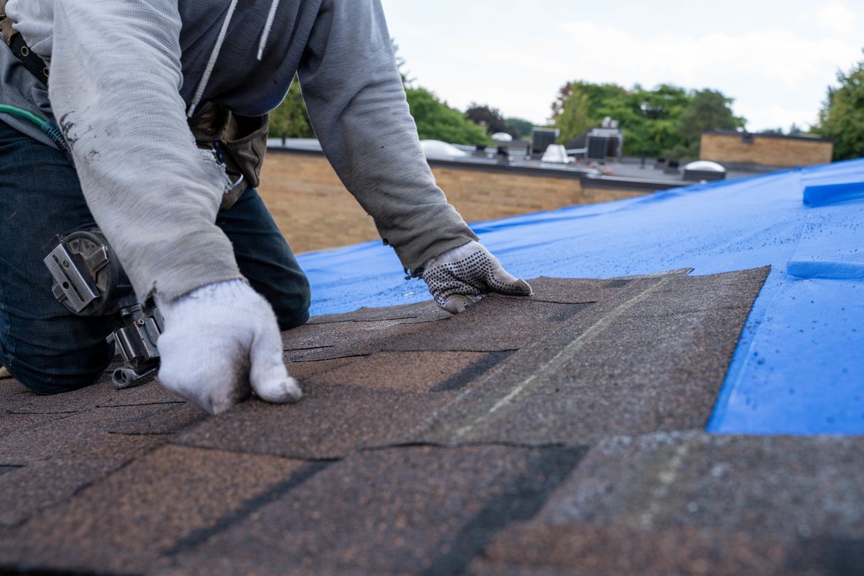 A man is working on a roof with a blue tarp.