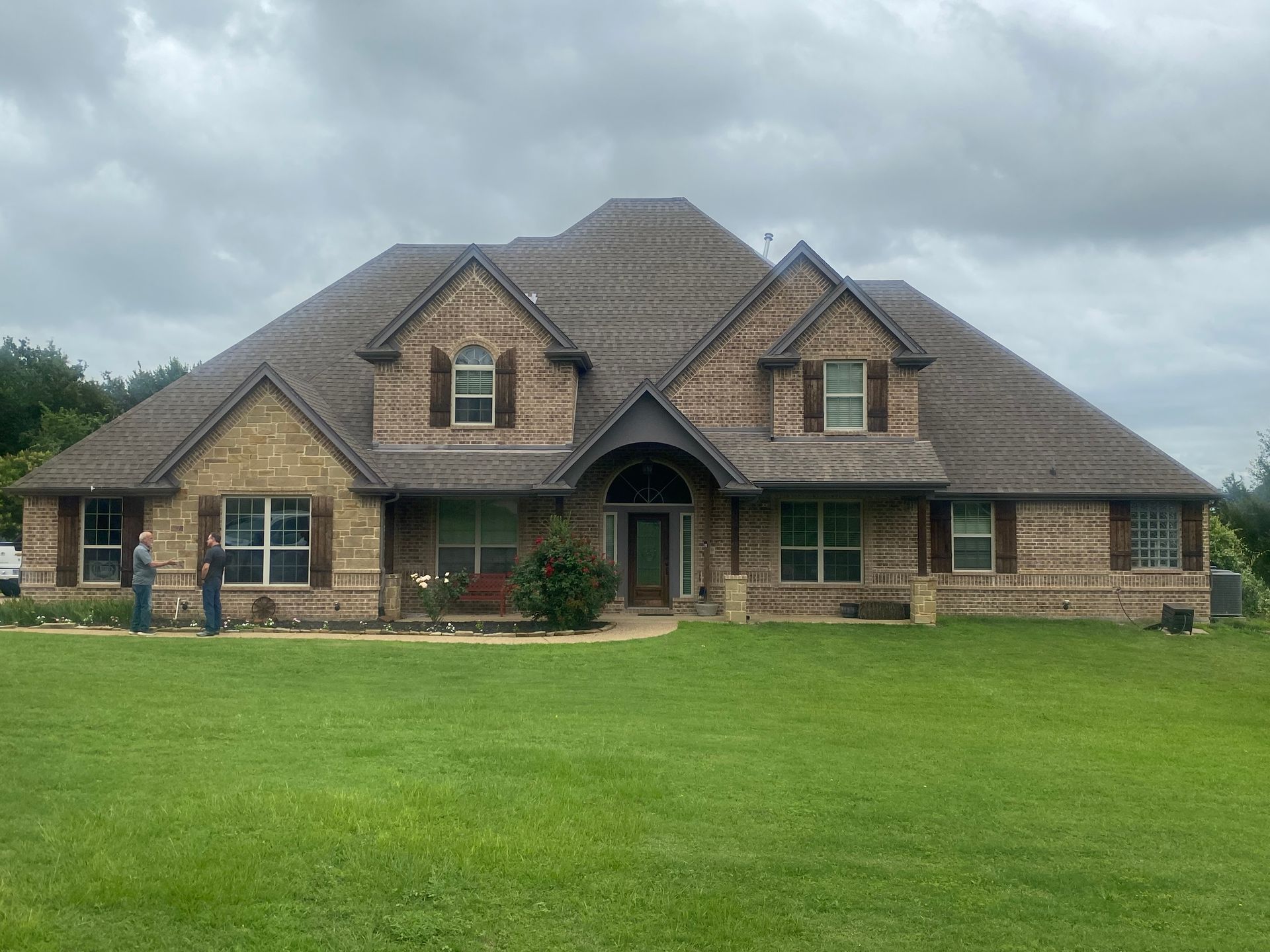 A large brick house with a large lawn in front of it.