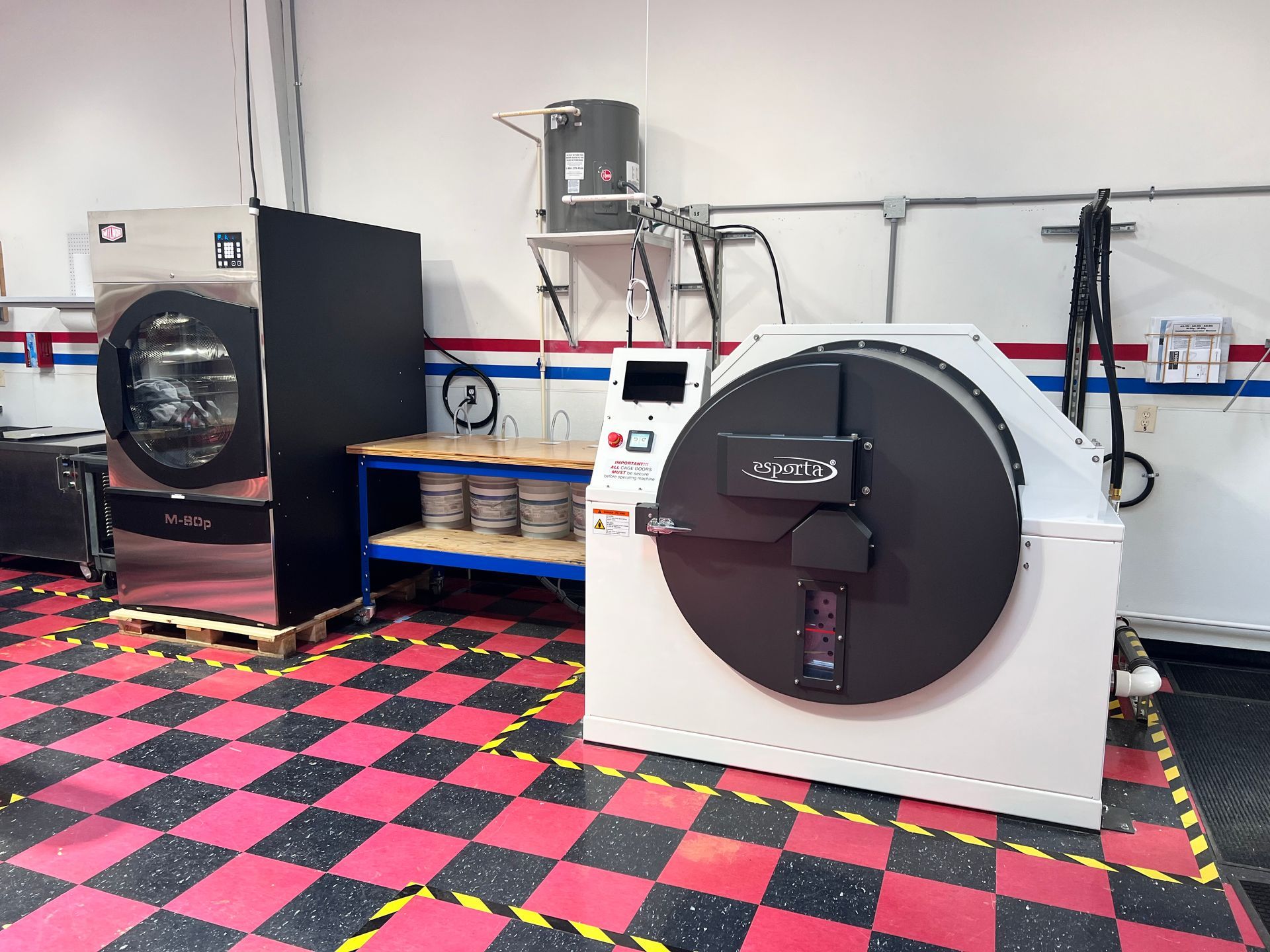 Blue dehumidifier in a laundry room with a dryer, clothes, and an outlet.