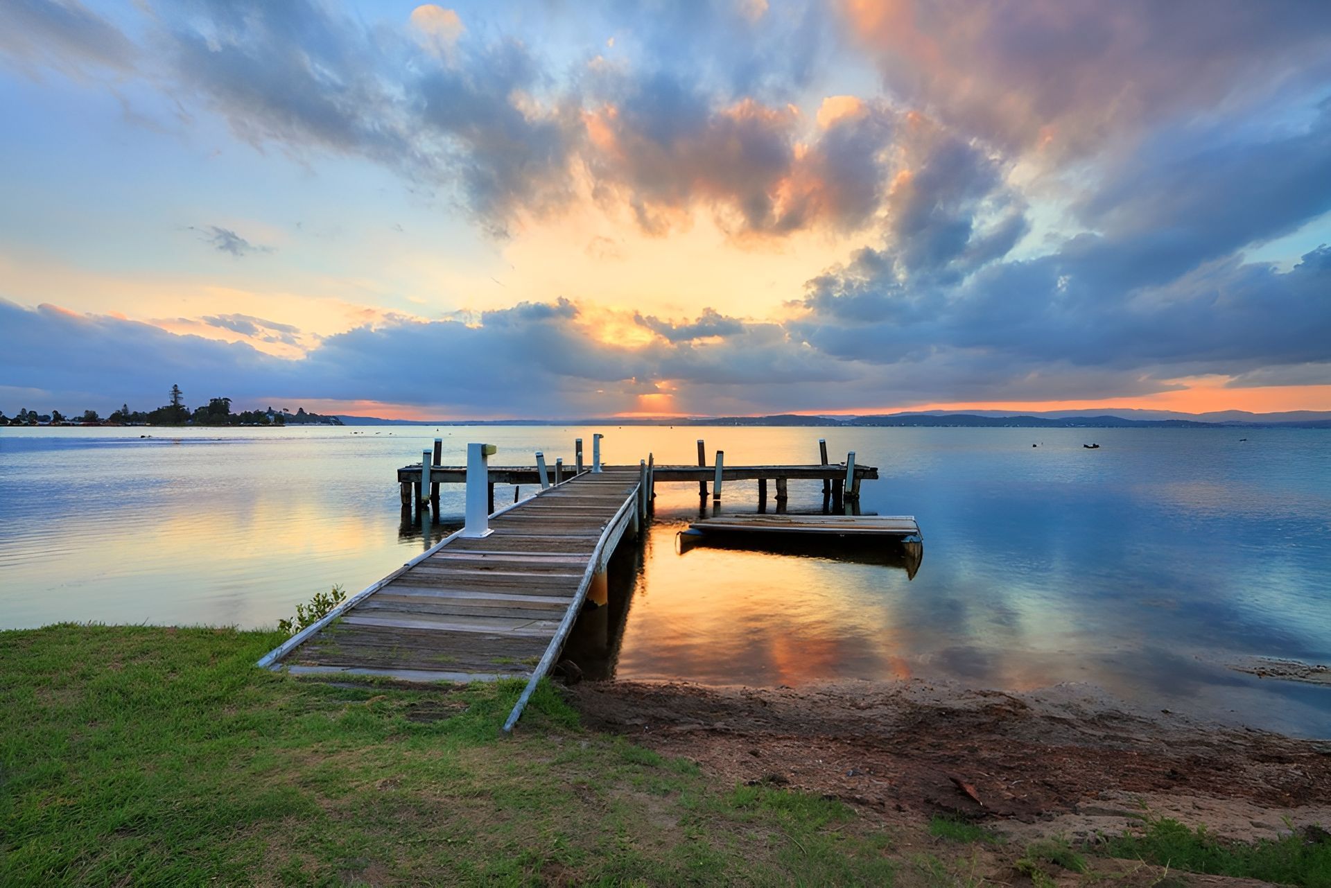 Wooden Pier Extends Into Calm Water Under a Vibrant Sunset Sky — M&J Marine Services in Forster, NSW