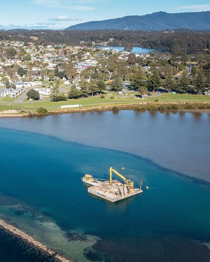 Dredge in Waterway Near Town, Dark Blue Water Meets Lighter Water with A Pier — M&J Marine Services in Newcastle, NSW