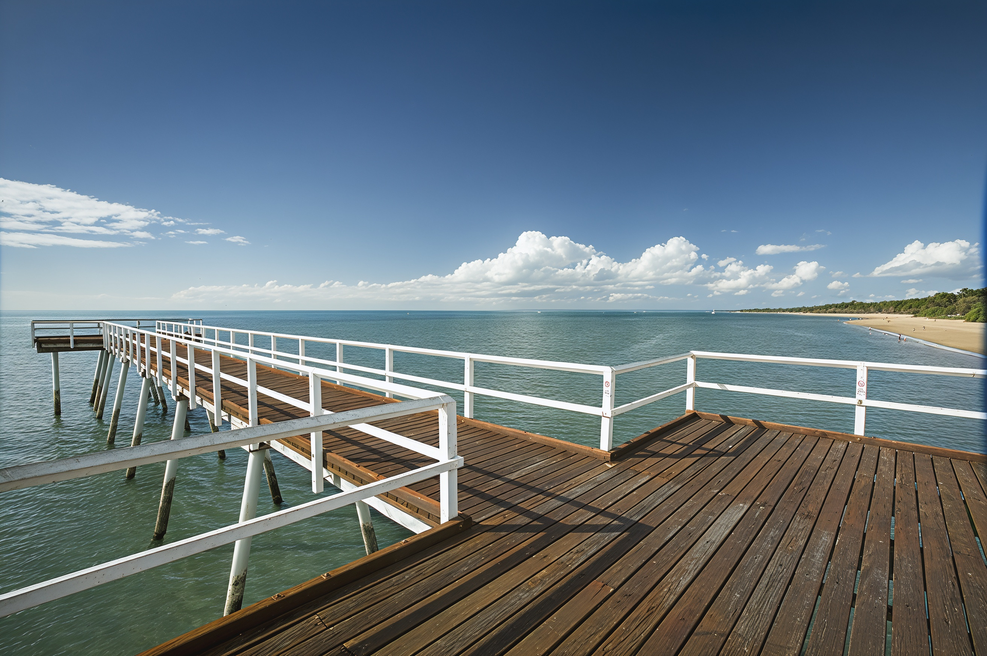 Wooden Pier Extending Into the Blue Ocean Under a Partly Cloudy Sky — M&J Marine Services in Forster, NSW