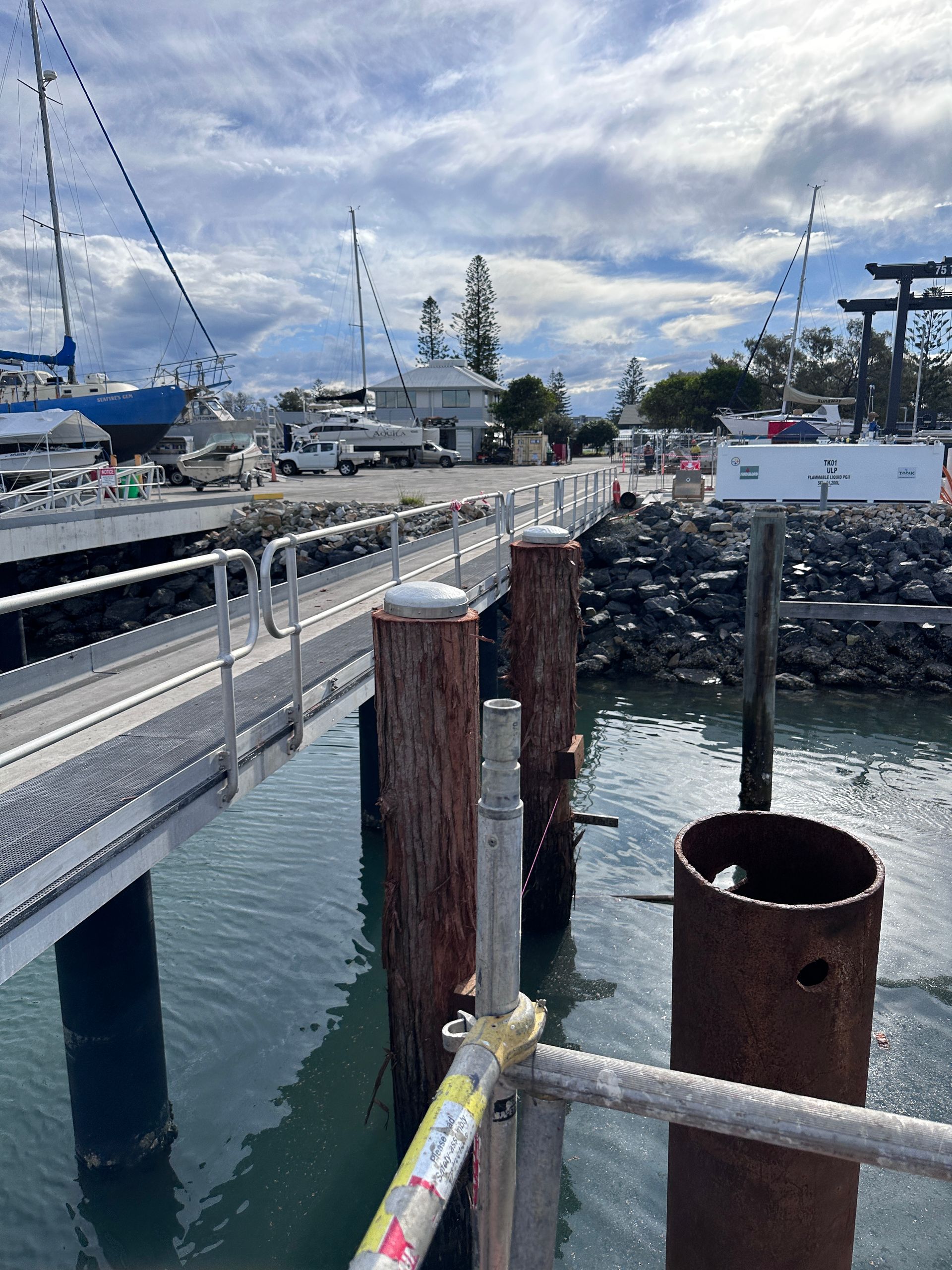 A Metal Walkway Leads to A Boat Yard with Parked Boats and Buildings — M&J Marine Services in Medowie, NSW