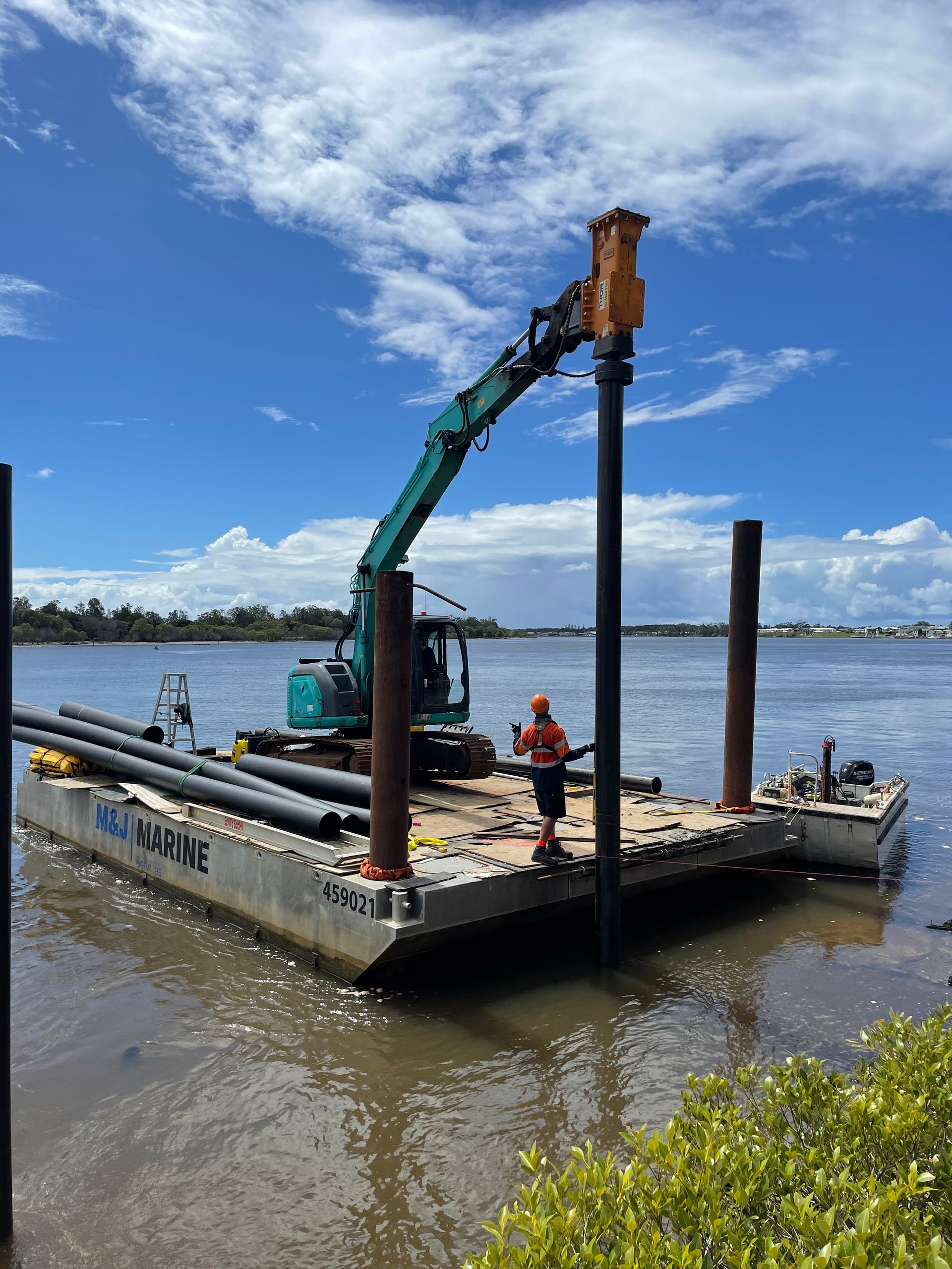 A Worker Operates an Excavator on A Floating Barge to Drive a Pile Into a River — M&J Marine Services in Lake Macquarie, NSW