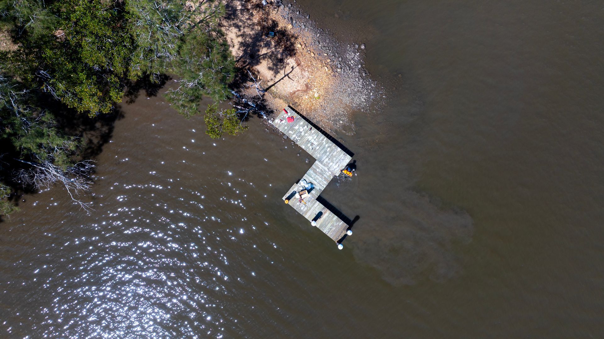 An Overhead Drone View of A Wooden Dock Extending Into Dark Water — M&J Marine Services in Newcastle, NSW