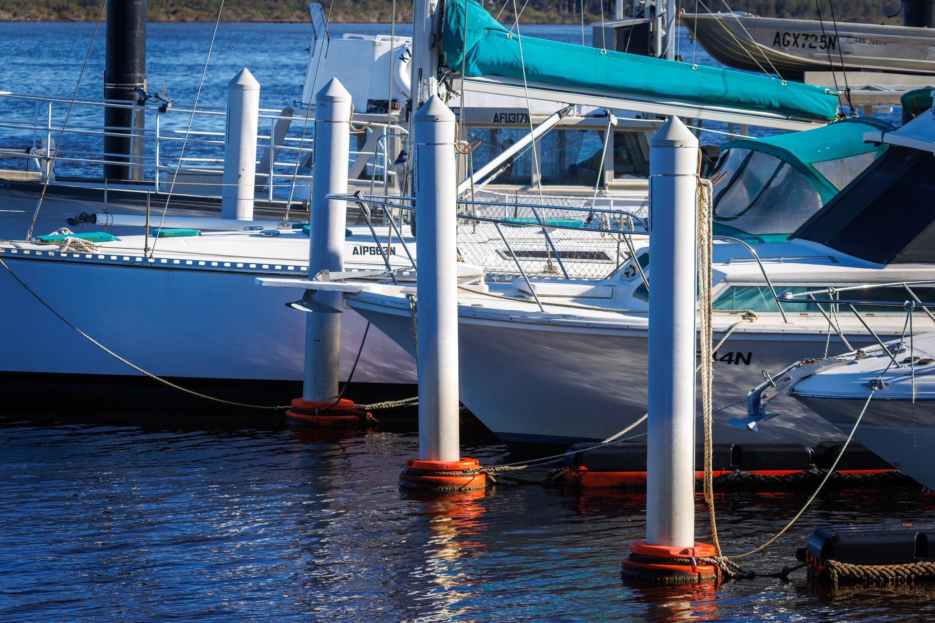 A Marina with Orange Rimmed White Pilings in The Water — M&J Marine Services in Forster, NSW