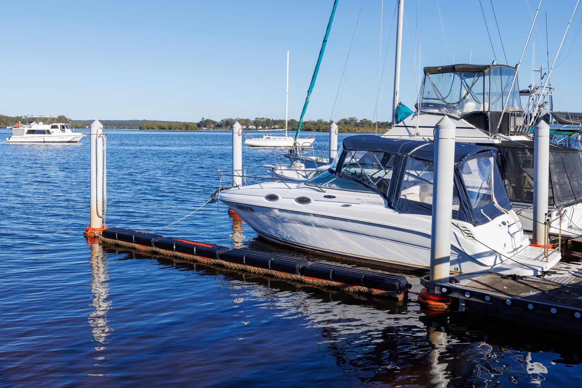 A White Powerboat with A Blue Canopy Docked at A Marina — M&J Marine Services in Forster, NSW