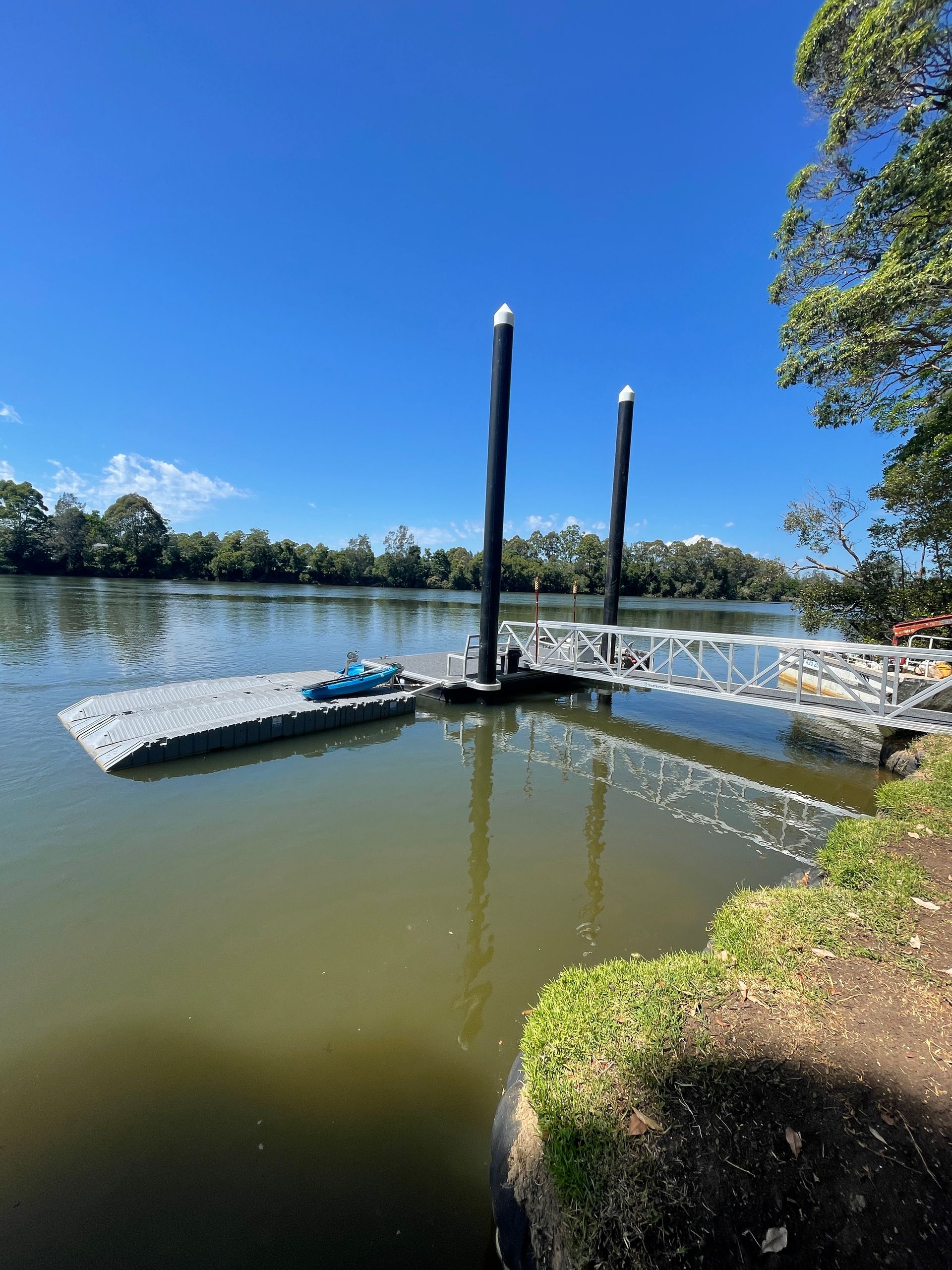 A Small Grey Floating Dock with A Blue Jet Ski Sits on A Calm River — M&J Marine Services in Lake Macquarie, NSW