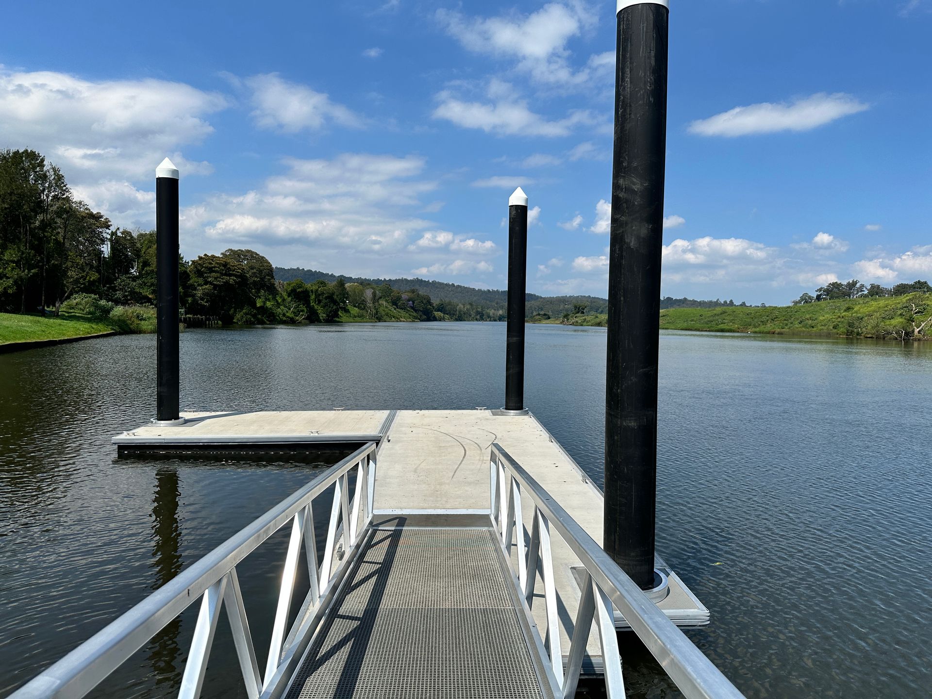 A Metal Ramp Leads onto A Floating Dock Anchored by Three Tall Black Pilings — M&J Marine Services in Coffs Harbour, NSW