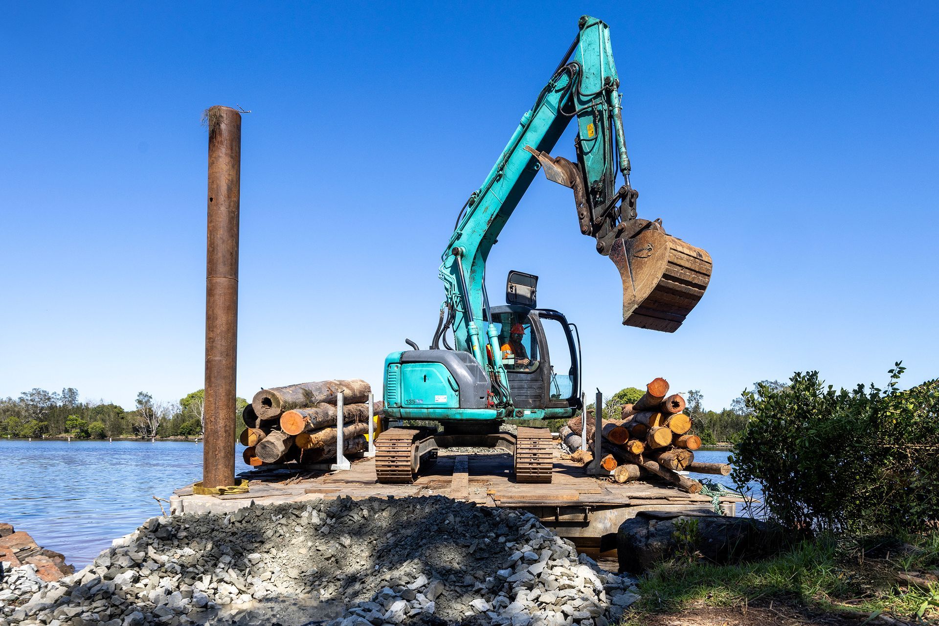 A Teal Excavator on A Floating Platform by A River — M&J Marine Services in Medowie, NSW