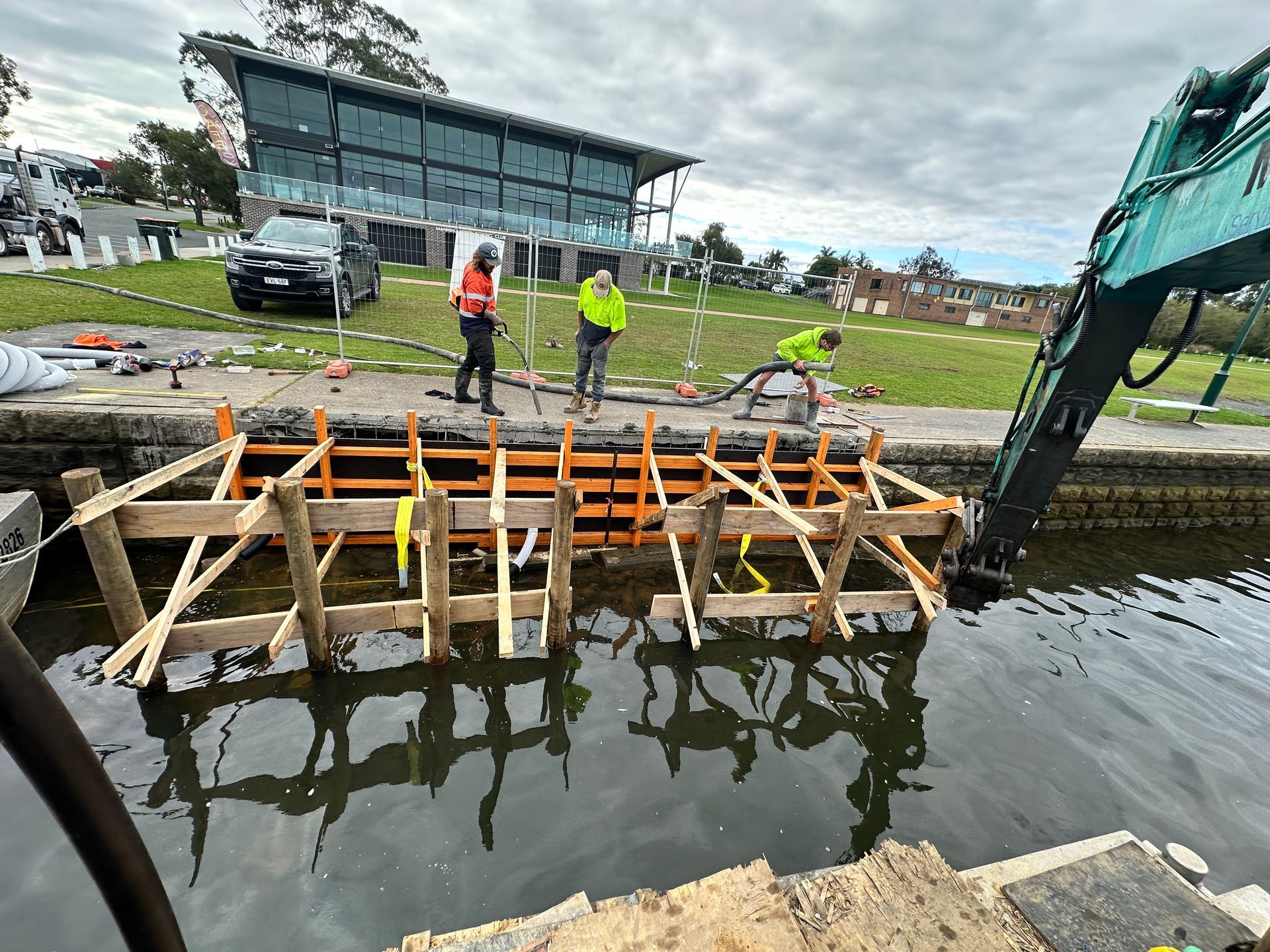 Workers Assemble Wooden Framework Along a Canal Bank — M&J Marine Services in Forster, NSW