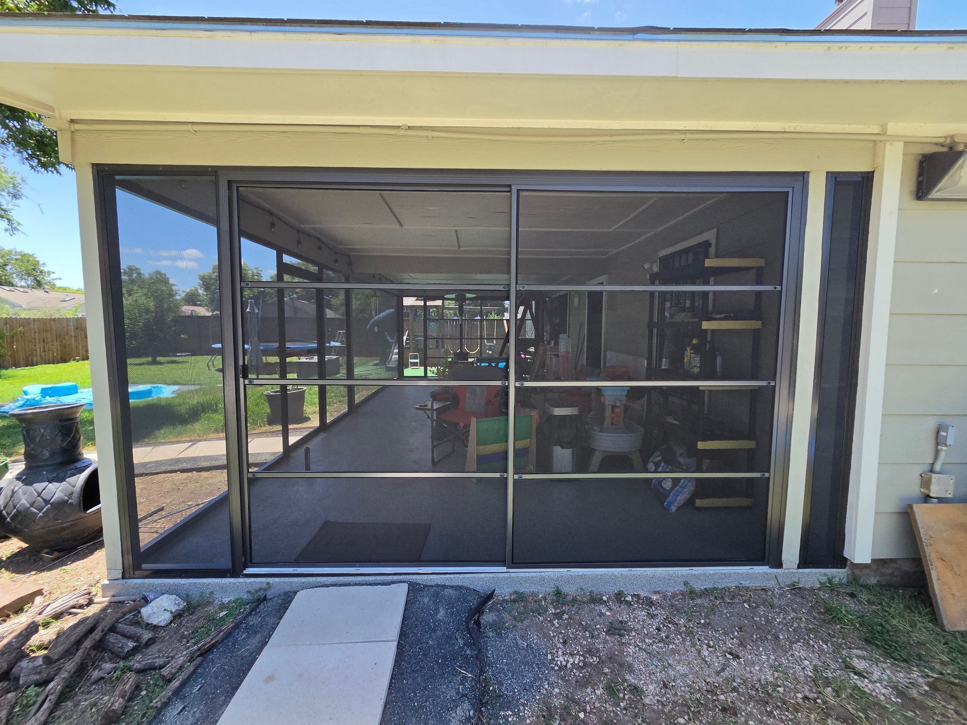 Screened patio enclosure with sliding glass doors and a concrete walkway in front