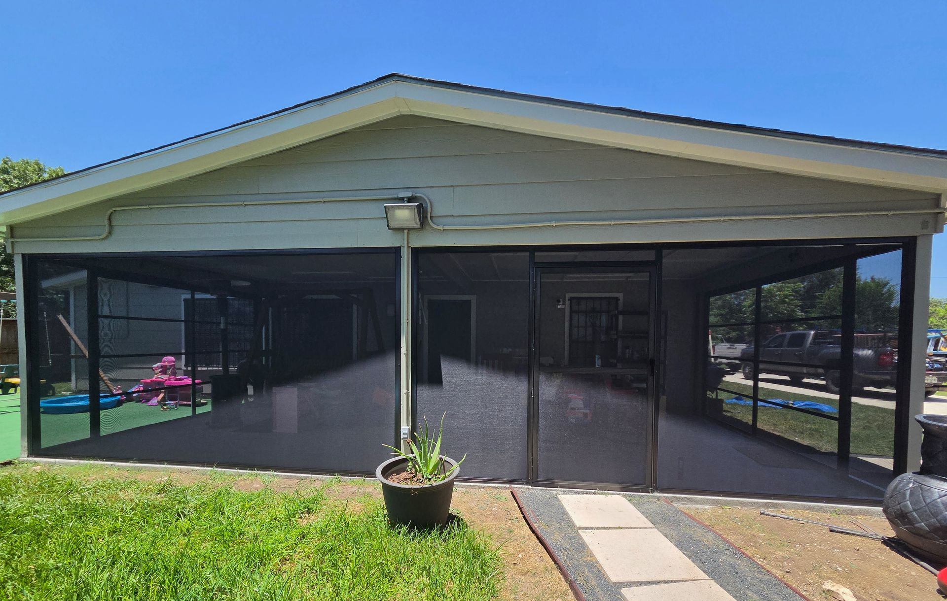 Small building entrance with screened porch, double doors, and a potted plant in front
