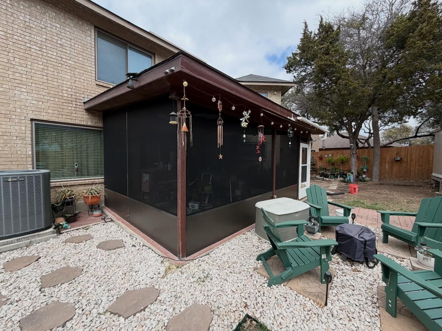 Back patio with screened gazebo, green chairs, gravel ground, and a house wall with windows