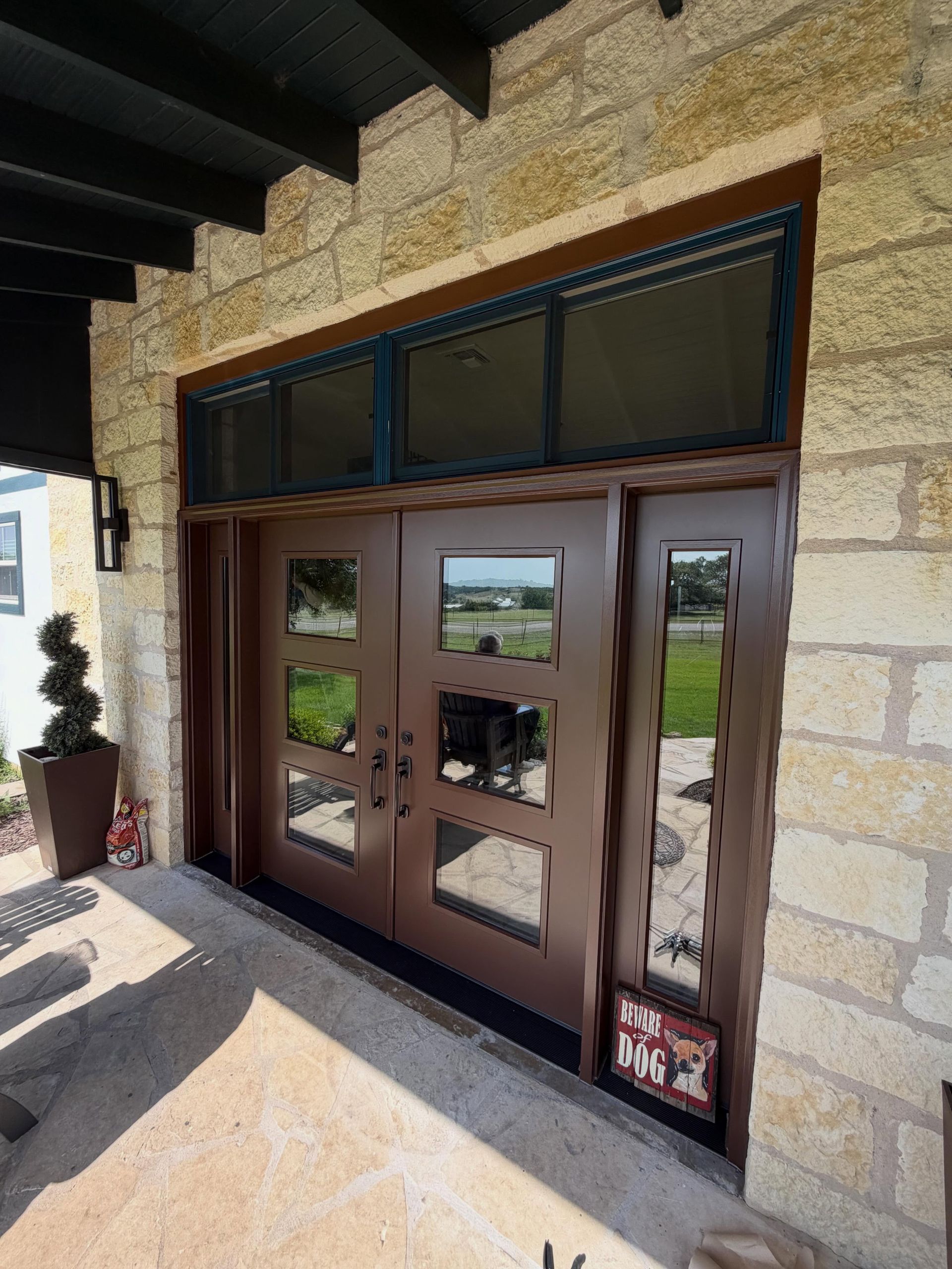 Glass double doors in a stone entryway with a transom window above