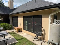 Patio with sliding glass door, bench, grill, and outdoor chair beside a beige house
