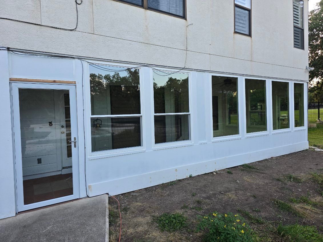White building exterior with a door and row of windows beside a dirt and grass path