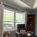 Bright living room with a recliner chair, large window, and dark wood corner shelf.