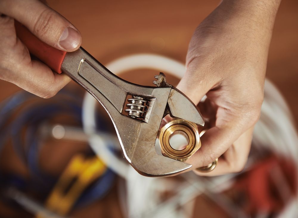 A Person Is Using An Adjustable Wrench To Fix A Faucet — Oceanforce Plumbing In Toronto, NSW