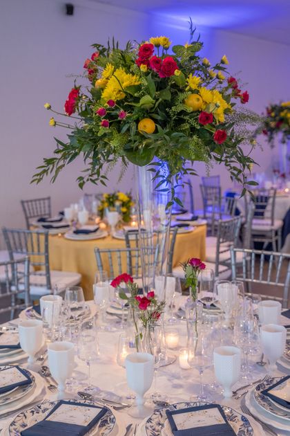 A table set for a wedding reception with a tall vase filled with flowers.