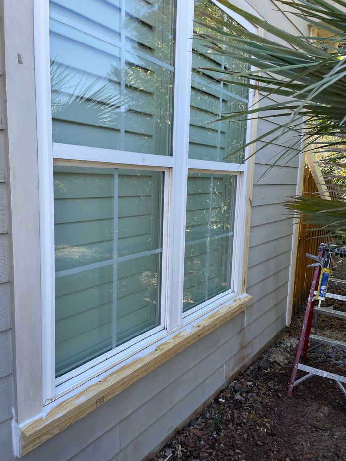 A window on the side of a house is being painted white.