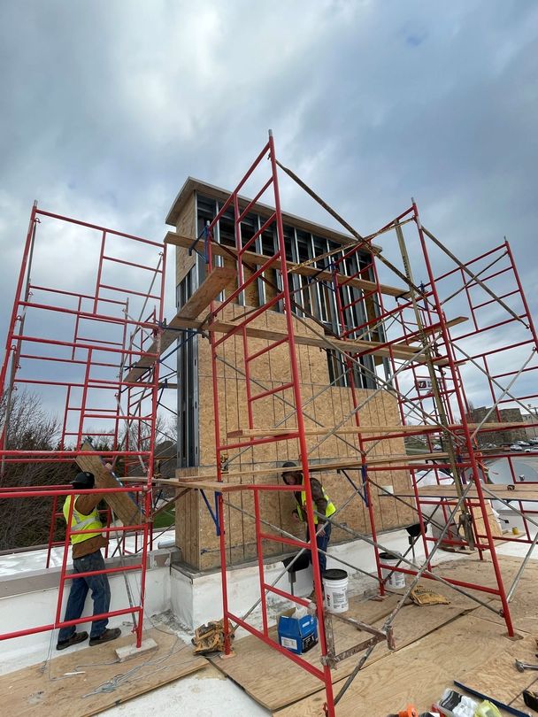 Wooden frame of a house under construction; sunlight streams through the open structure.