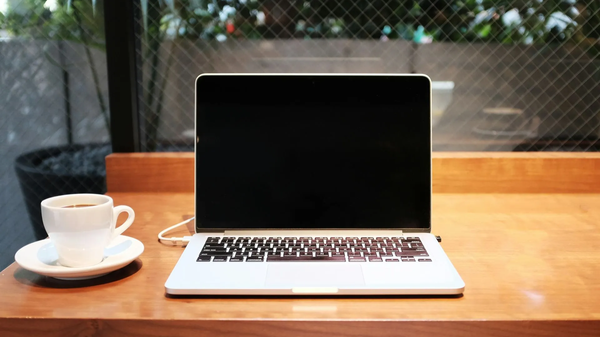 laptop on wood table next to cup of coffee