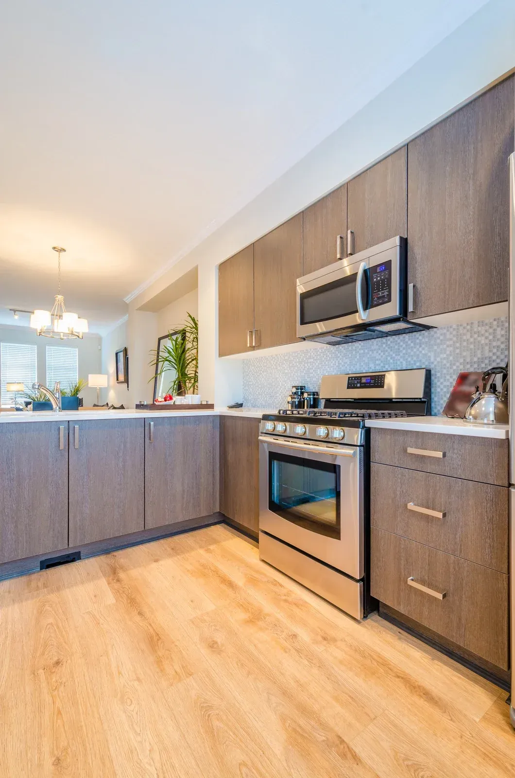 Modern kitchen with gray cabinets, stainless steel appliances, and wood flooring.