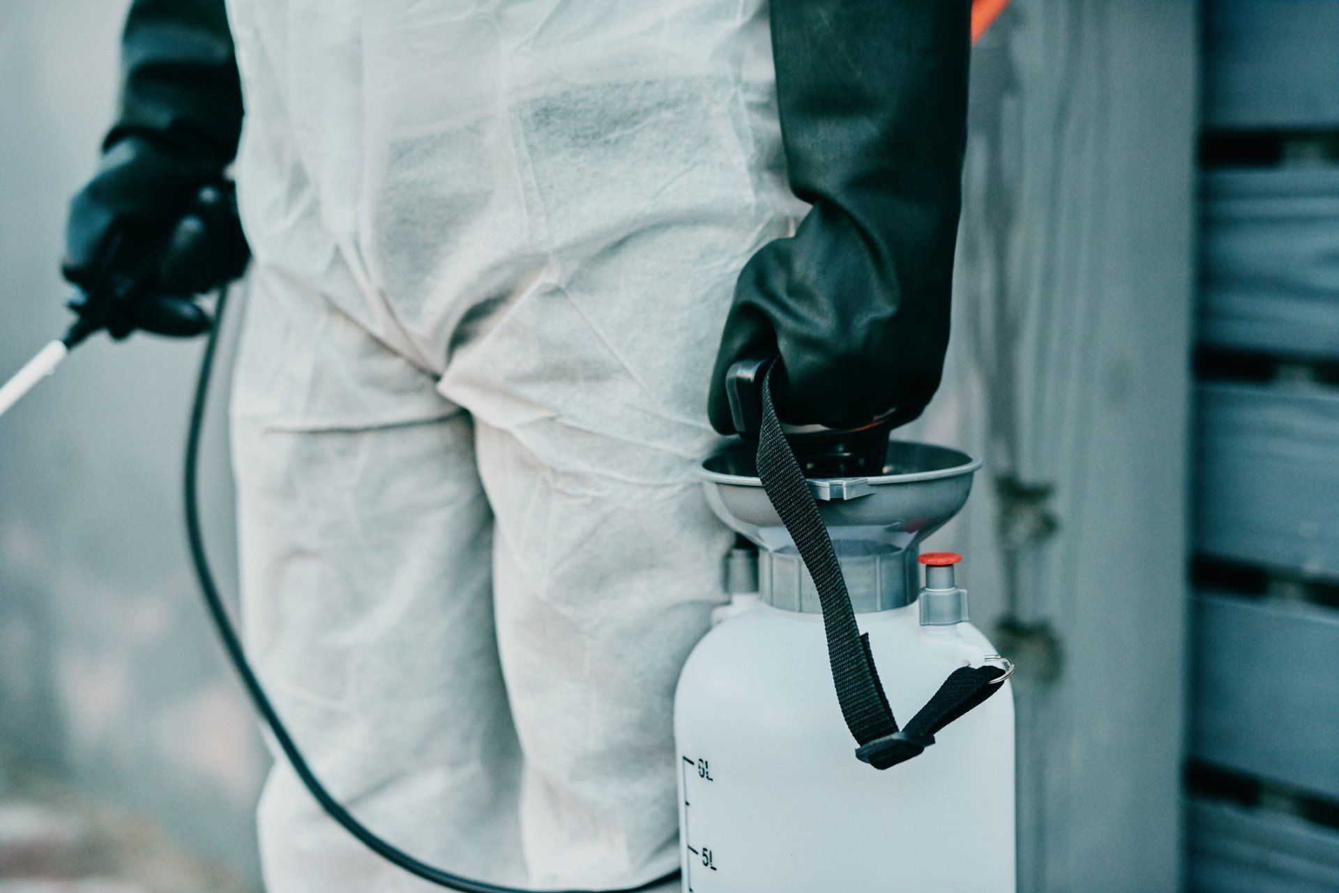 A man in a protective suit is spraying something with a sprayer.