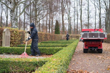 Man in black jacket and hat sweeping leaves, part of deceased estate cleanup efforts.