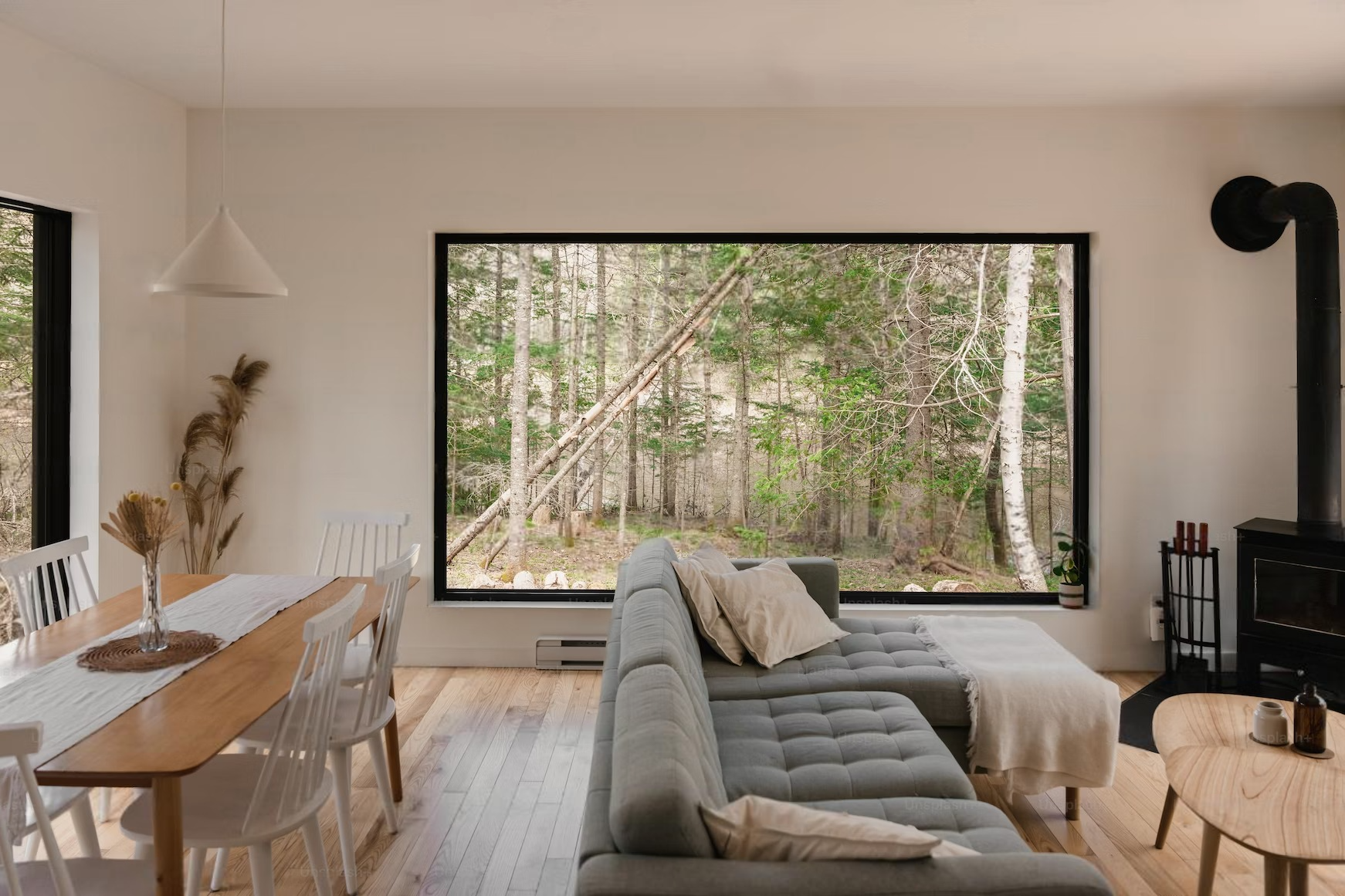 a living room with a couch , table , chairs and a large window .