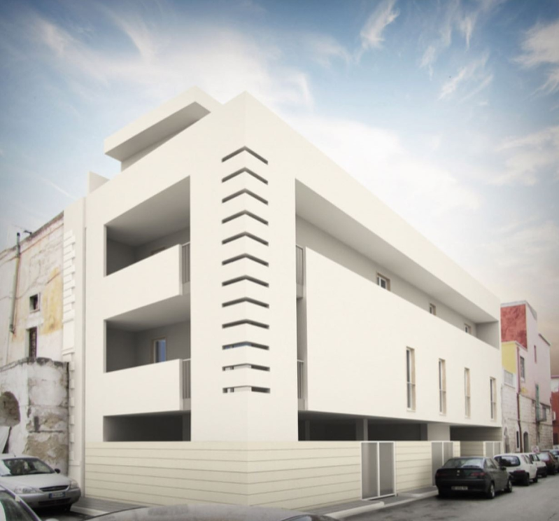 Moderno palazzo residenziale bianco all'angolo di una strada, sotto un cielo luminoso.