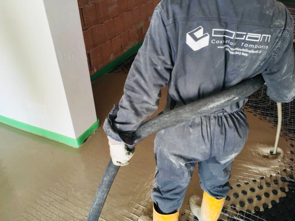 Un operaio aspira la polvere dal pavimento durante le pulizie di un cantiere.