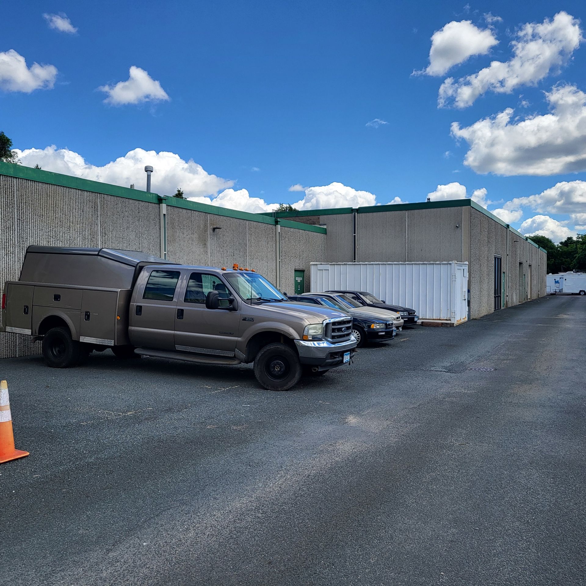A large industrial building with a lot of windows and a parking lot in front of it.