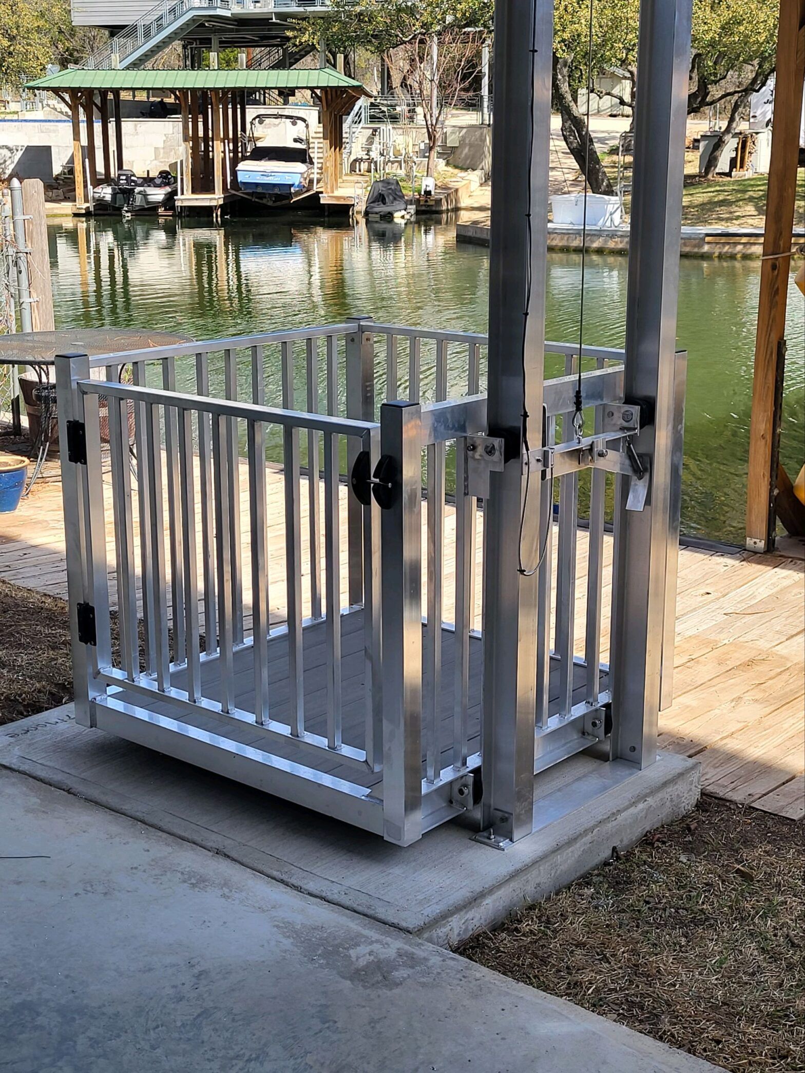 silver aluminum cargo lift installed on a lakeside dock with boats in the background