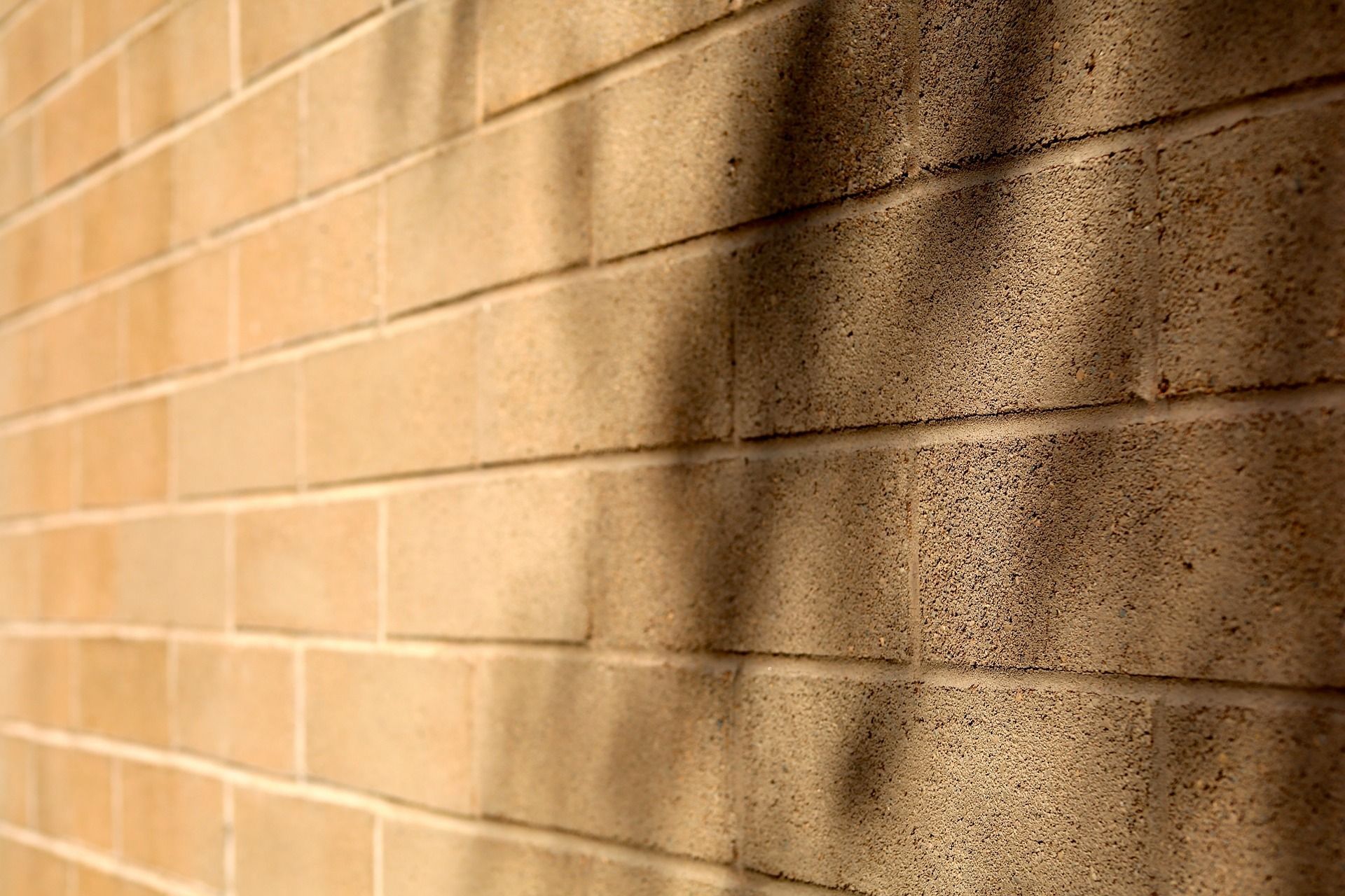 Mur de briques beiges avec des ombres projetées sur le côté droit.