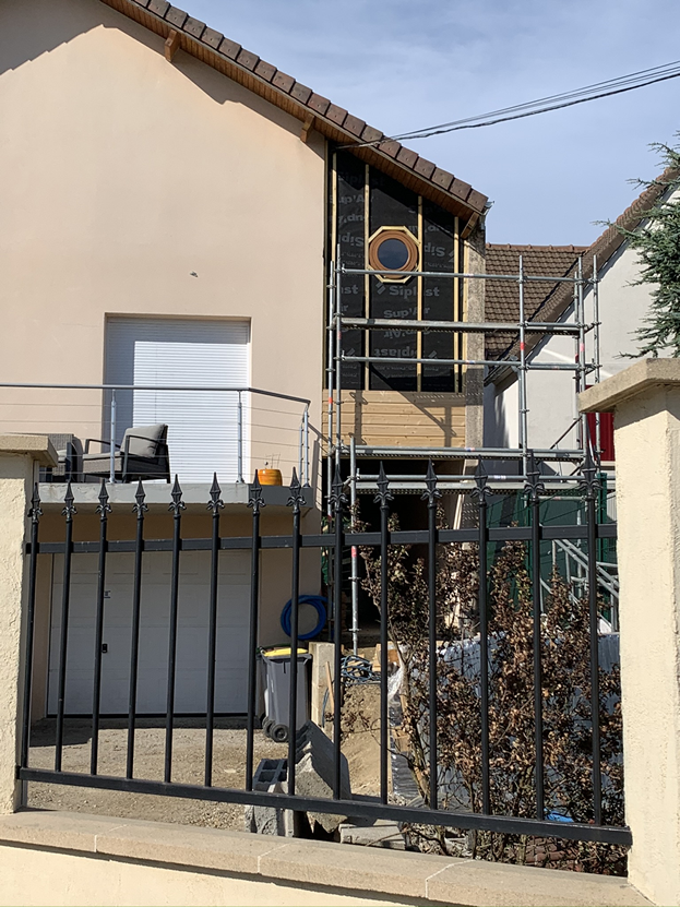 Extérieur de la maison avec échafaudages, portail et mur partiellement construit.